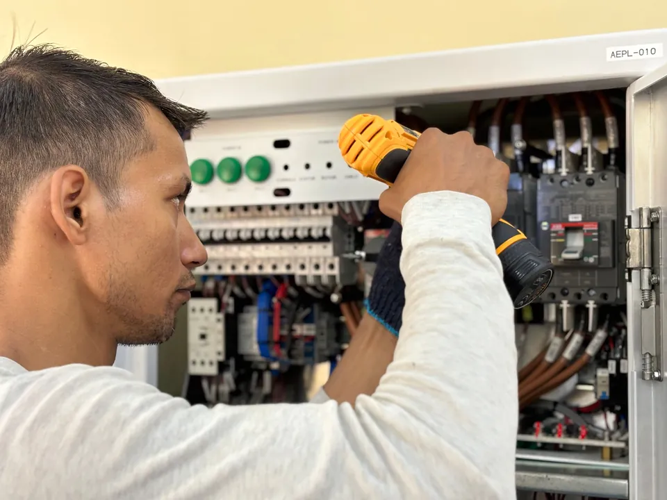Technicien raccordant une armoire électrique